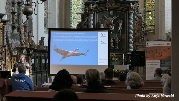 Günter gives a presentation in front of several people sitting in pews inside a church. Text: Photo by Anja Nowald