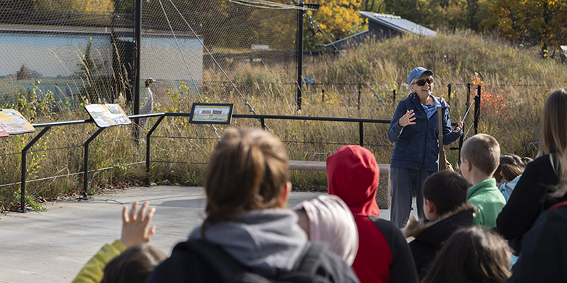 A volunteer naturalist leads a school group tour at our headquarters, with the Sarus Cranes in the background. Hannah Jones/International Crane Foundation